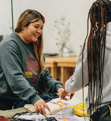 Two people engaging in a craft activity together, with one person smiling and the other interacting.